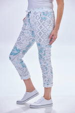 Side image of heart print pants. Pull on printed jeggings. White and blue printed pants. 