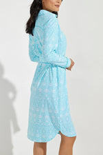 Side image of Coolibar Kitts dress. Long sleeve button front dress in blue floral print. 